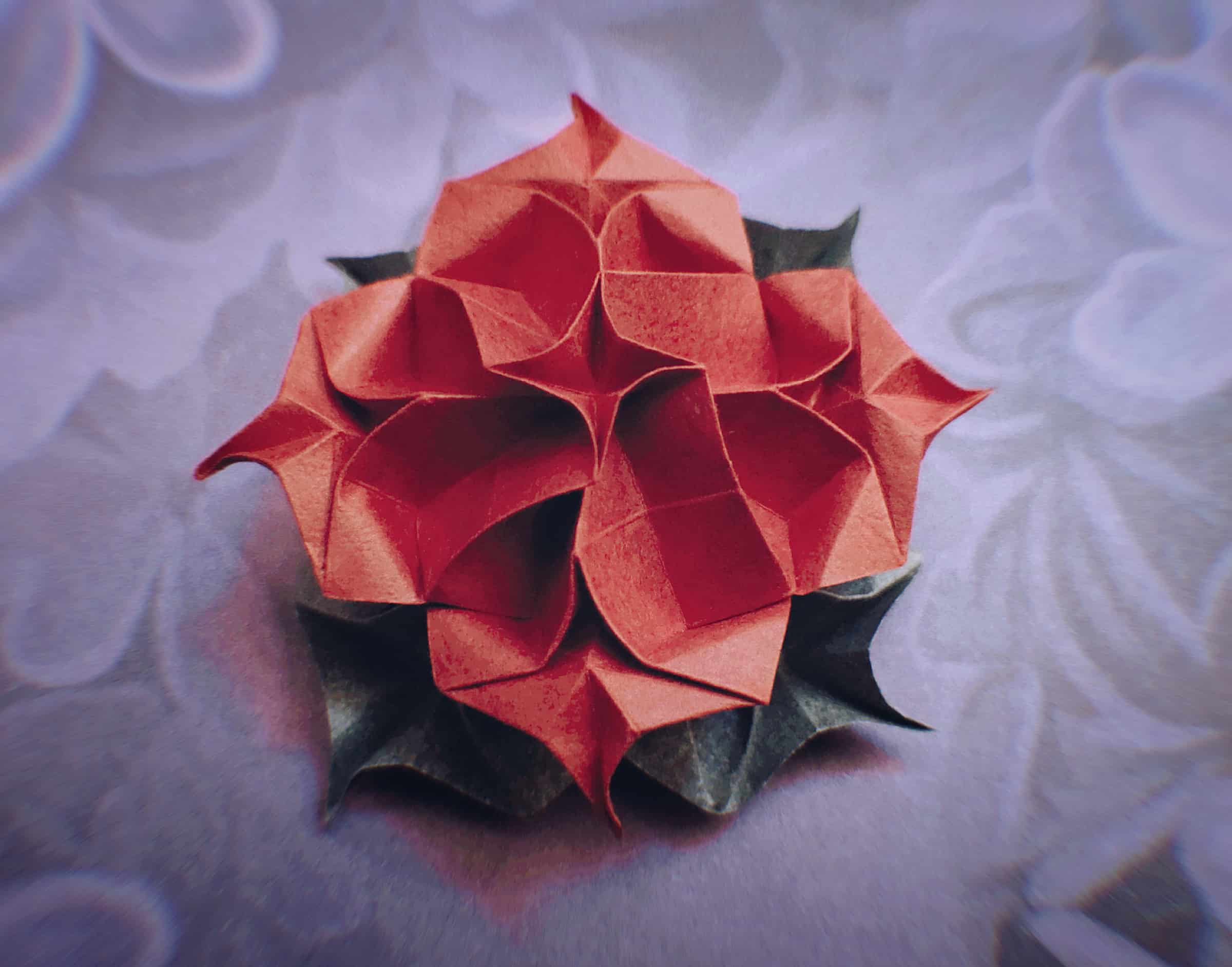 a bright red origami flower with layered swirl patterns
